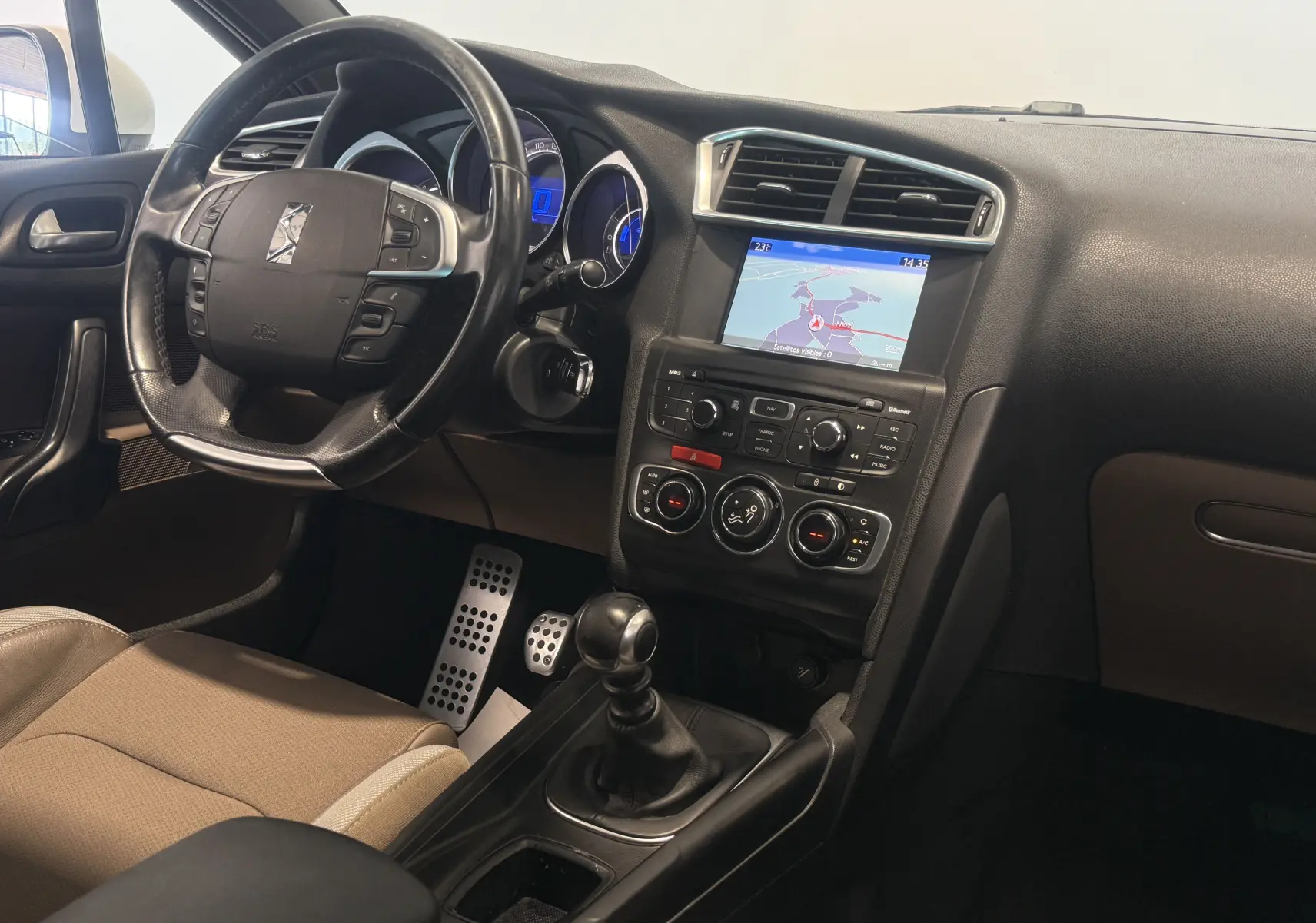 Intérieur de la Citroën DS4 2012 vue côté conducteur, tableau de bord noir avec écran GPS et levier de vitesse manuel.