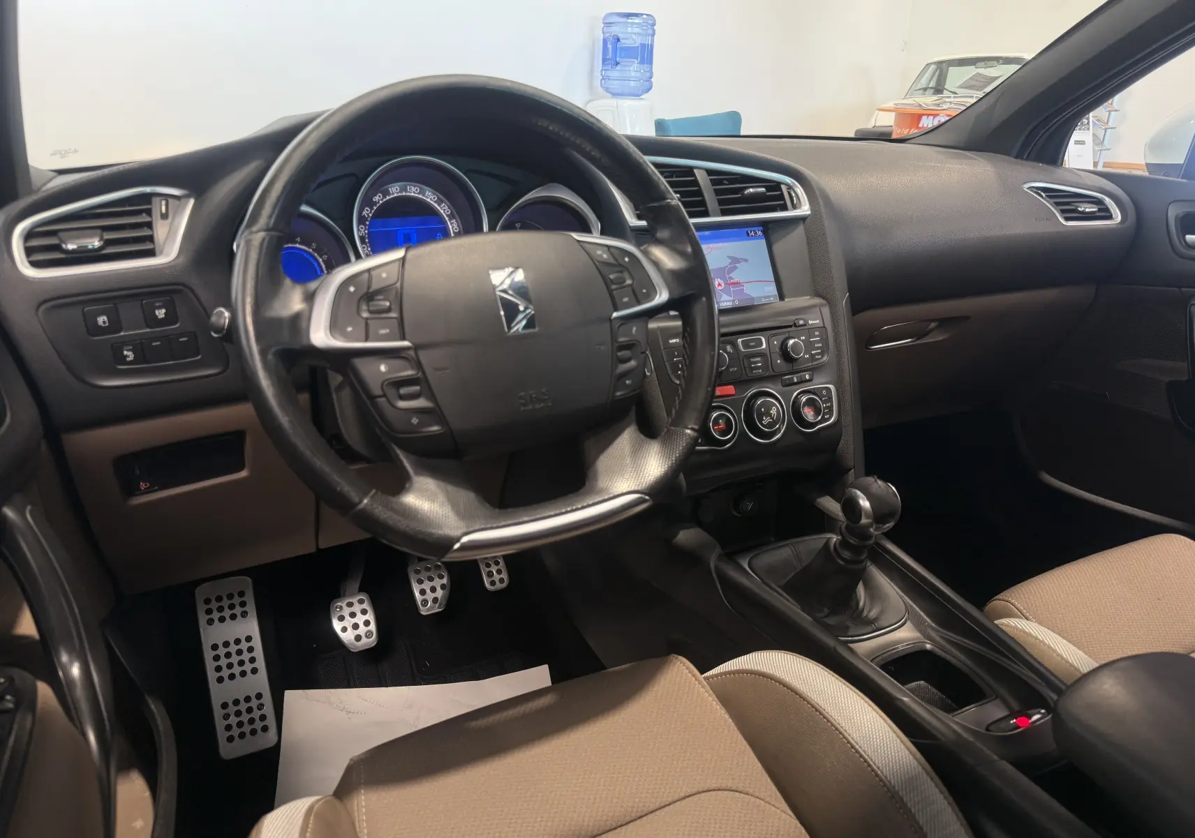 Vue intérieure avant du Citroën DS4 blanc de 2012, montrant le volant, la console centrale et la boîte manuelle.