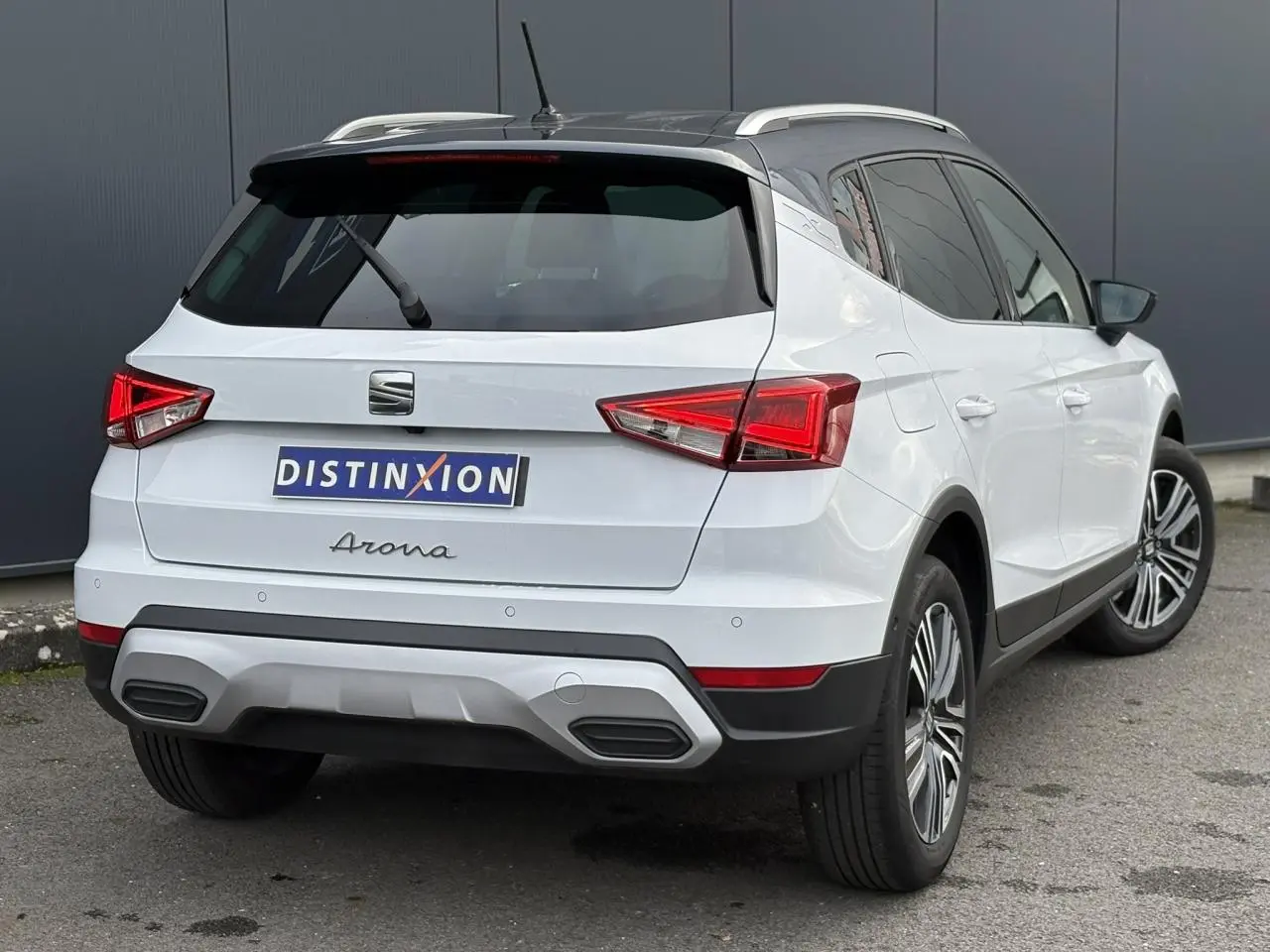 Vue 3/4 arrière droite d'un SEAT Arona blanc Nevada avec toit noir et feux arrière LED triangulaires.