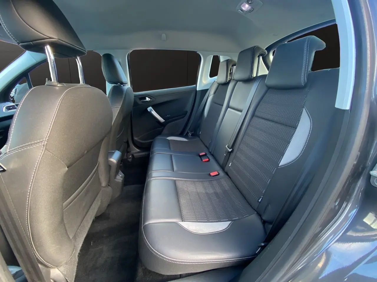 Vue intérieure côté arrière droit du Peugeot 2008 gris platinium, montrant les sièges arrière en tissu et cuir noir.