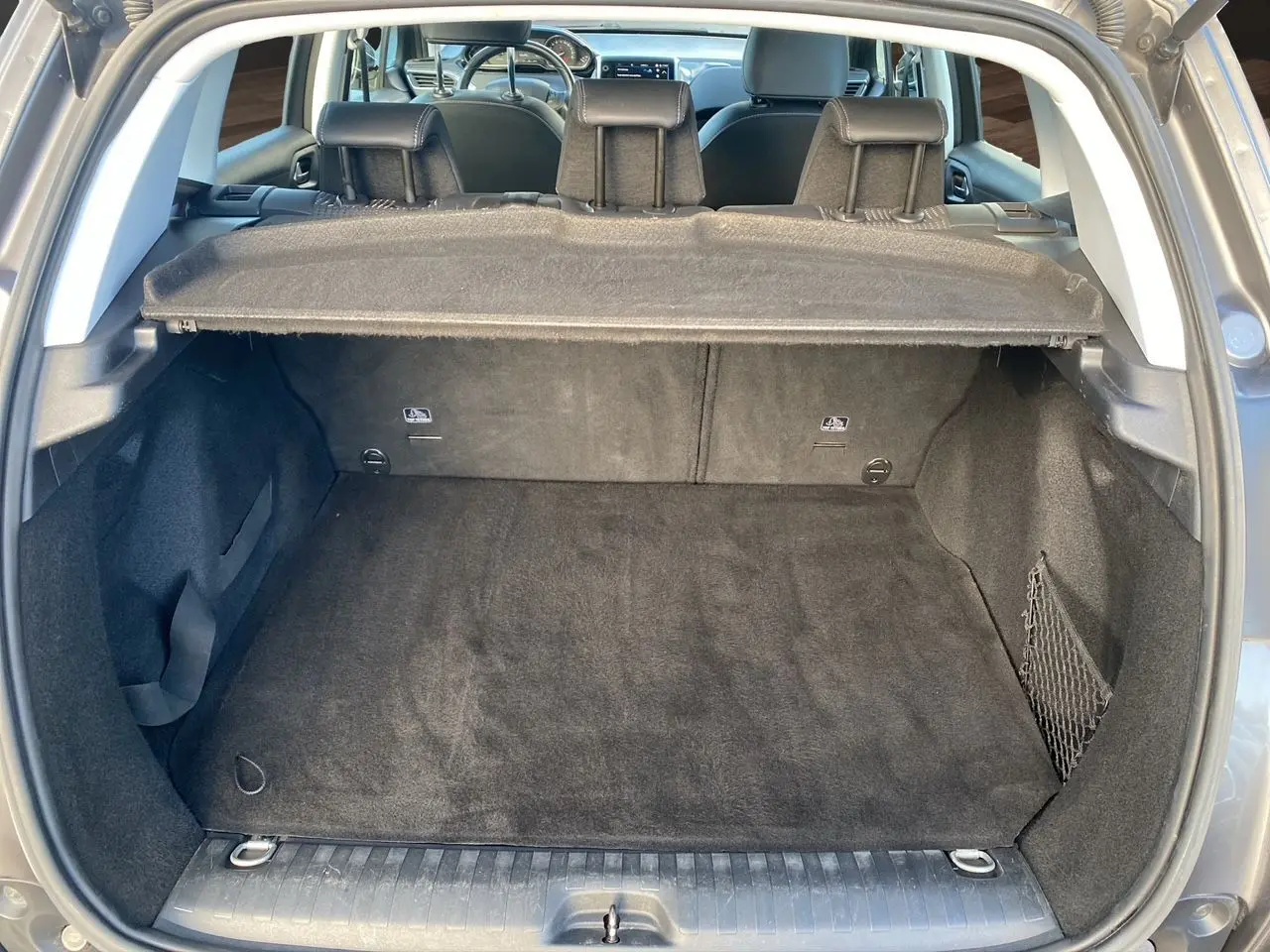 Coffre ouvert en vue arrière d’un Peugeot 2008 gris platinium, montrant l’espace de chargement et la plage arrière.