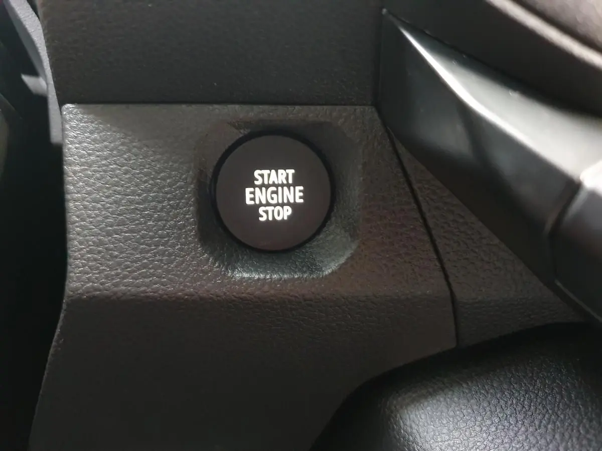 Gros plan sur le bouton Start Engine Stop noir dans l'habitacle du Dacia Duster blanc Glacier 2025.
