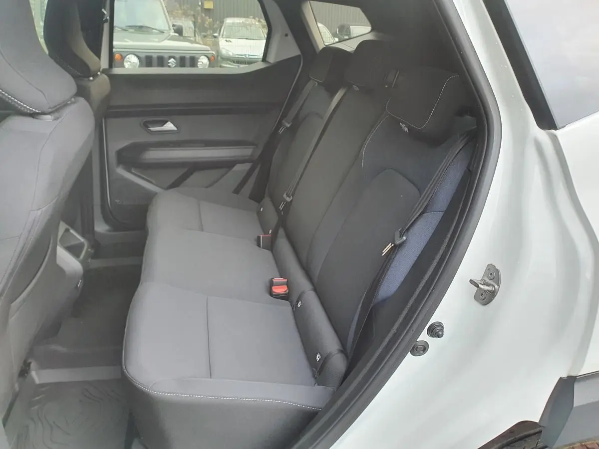 Vue intérieure côté gauche de la banquette arrière noire du Dacia Duster blanc glacier avec ceintures trois points et prises USB.