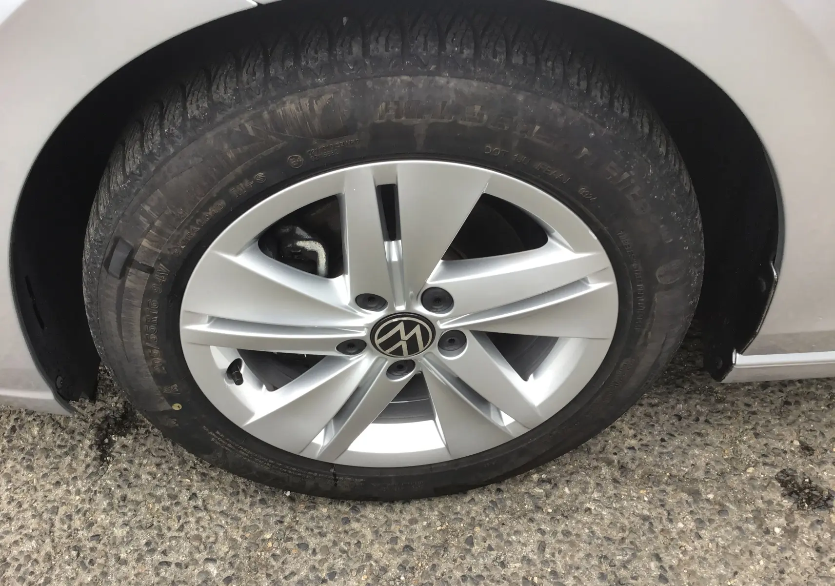 Gros plan sur la roue avant gauche d'une Volkswagen Golf VIII gris reflex avec jante alliage 16 pouces.