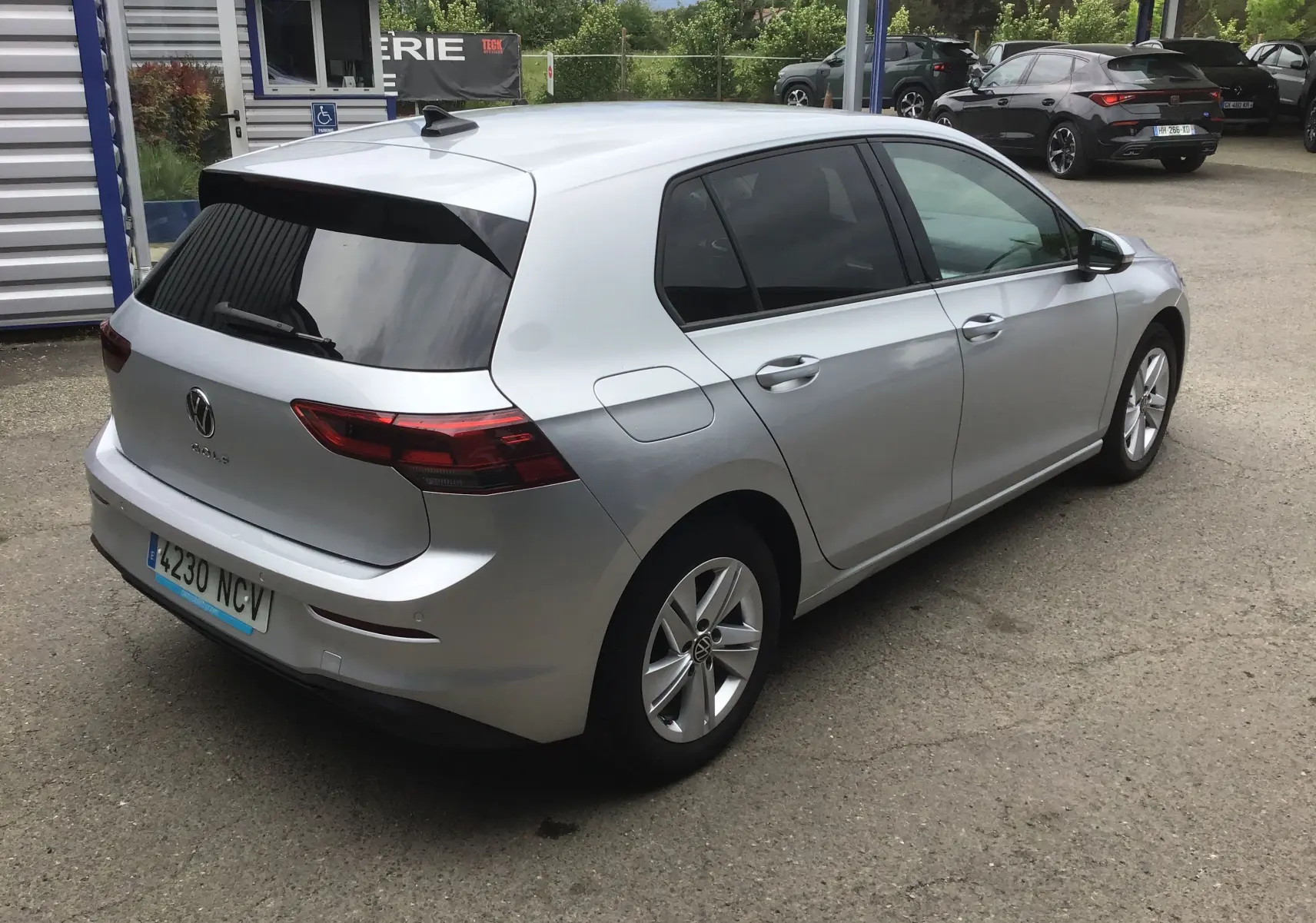Vue 3/4 arrière droite d'une Volkswagen Golf VIII gris reflex avec vitres teintées et jantes alliage 16 pouces.