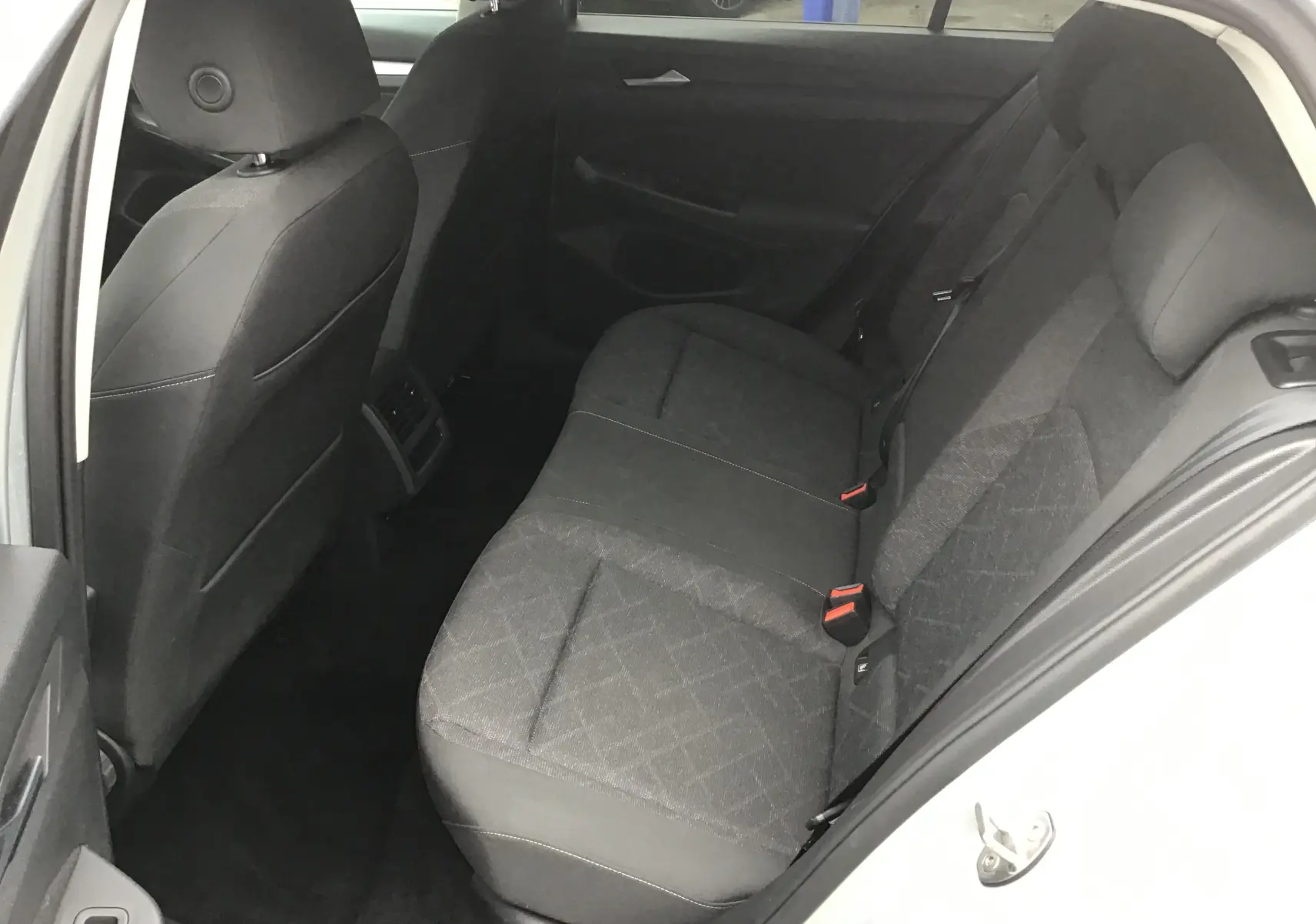 Vue intérieure côté droit des sièges arrière gris foncé d'une Volkswagen Golf VIII 2020, tissu avec motifs discrets.