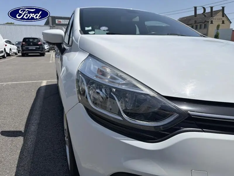 Gros plan sur l'avant droit blanc d'une Renault Clio 2018, mettant en valeur le phare et la calandre noire.