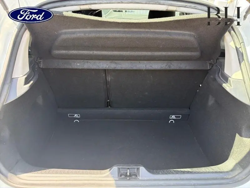 Coffre ouvert vu de l'arrière d'une Renault Clio blanche, montrant un espace de chargement vide avec cache-bagages.