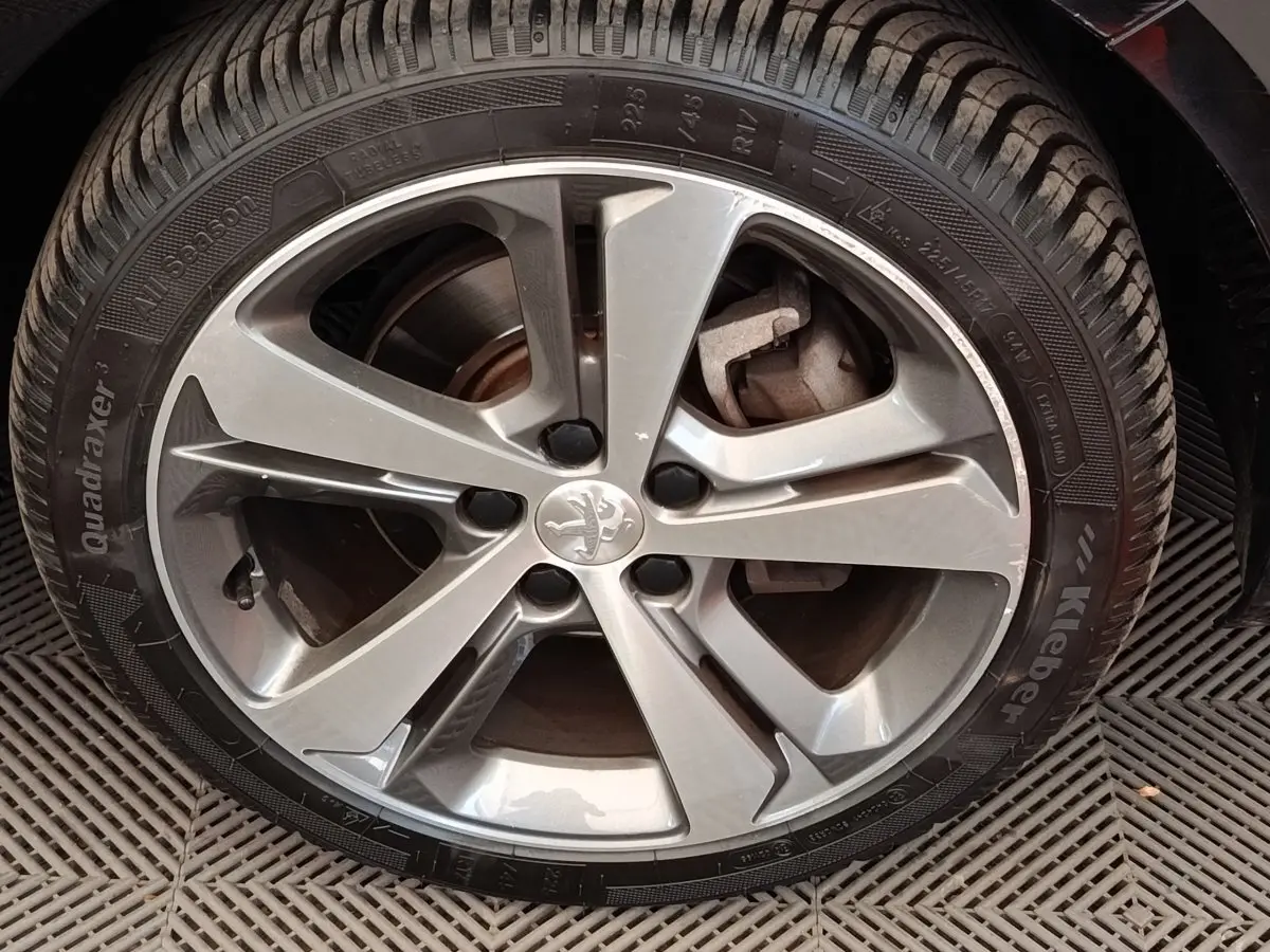 Gros plan sur la jante alliage argentée avec logo Peugeot au centre, montée sur pneu Kleber All Season.