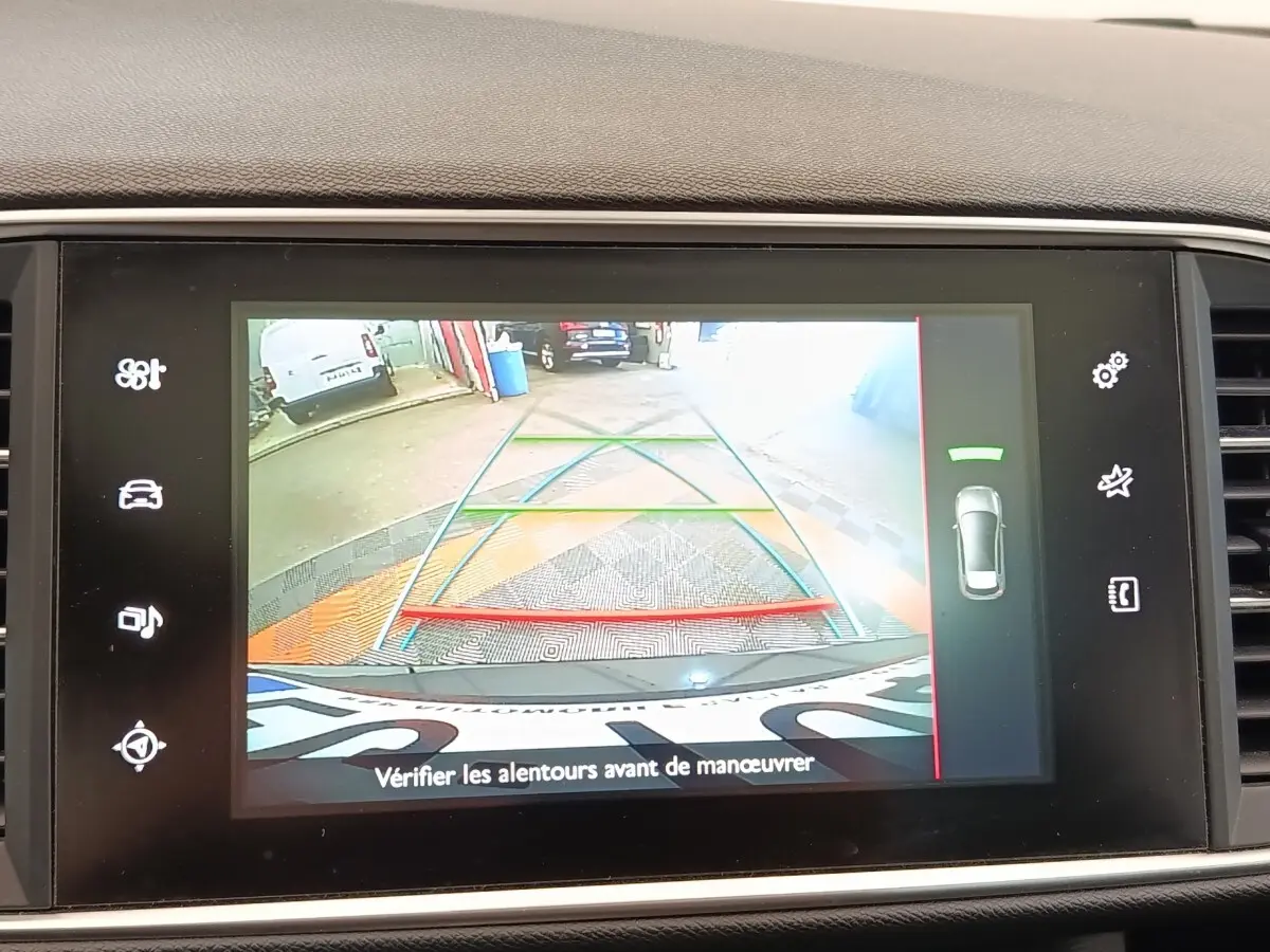 Écran tactile intérieur montrant la caméra de recul avec lignes de guidage colorées sur Peugeot 308 noir, vue arrière.