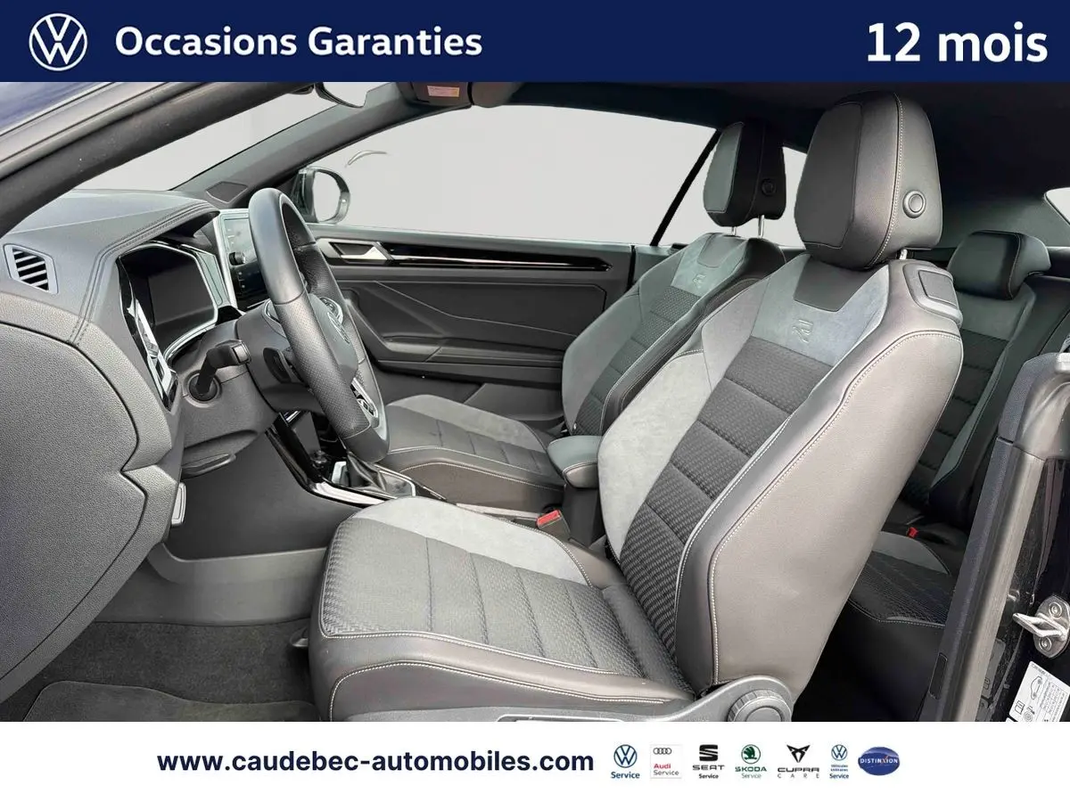 Vue intérieure côté conducteur du Volkswagen T-Roc Cabriolet noir 2025, sièges sport bi-matière avec logo R-Line.