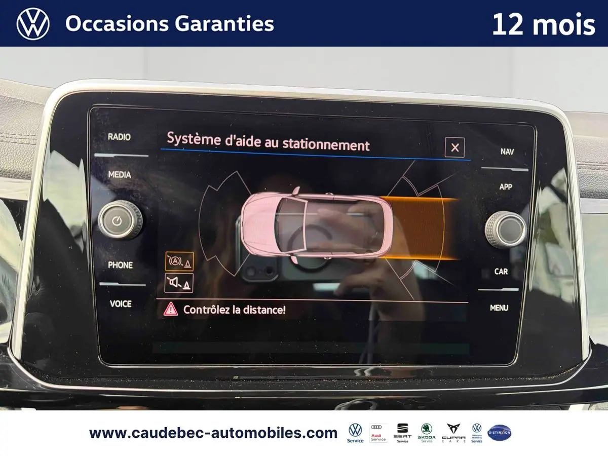 Vue rapprochée de l’écran tactile du Volkswagen T-Roc Cabriolet noir affichant l’aide au stationnement active.