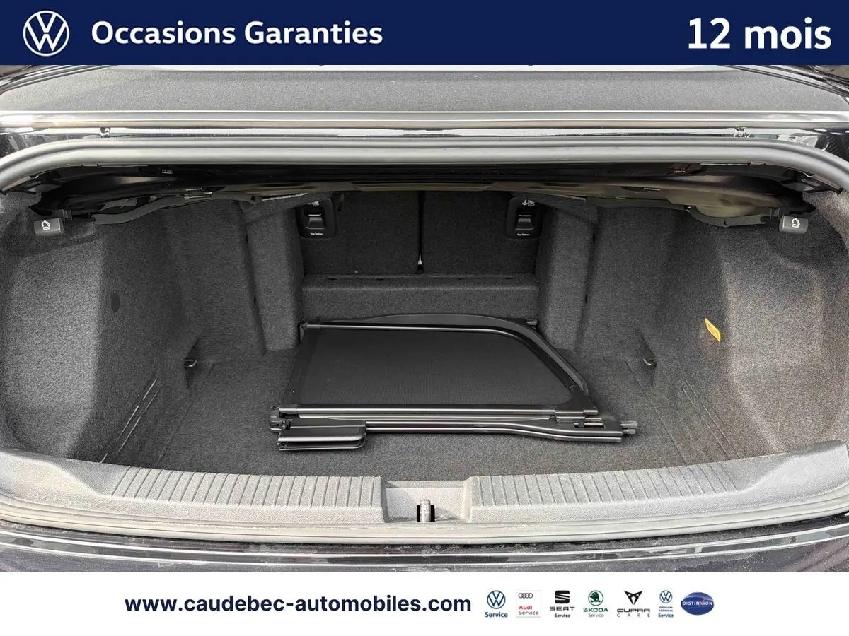 Coffre ouvert du Volkswagen T-Roc Cabriolet noir, vue intérieure montrant un filet de séparation plié au sol.