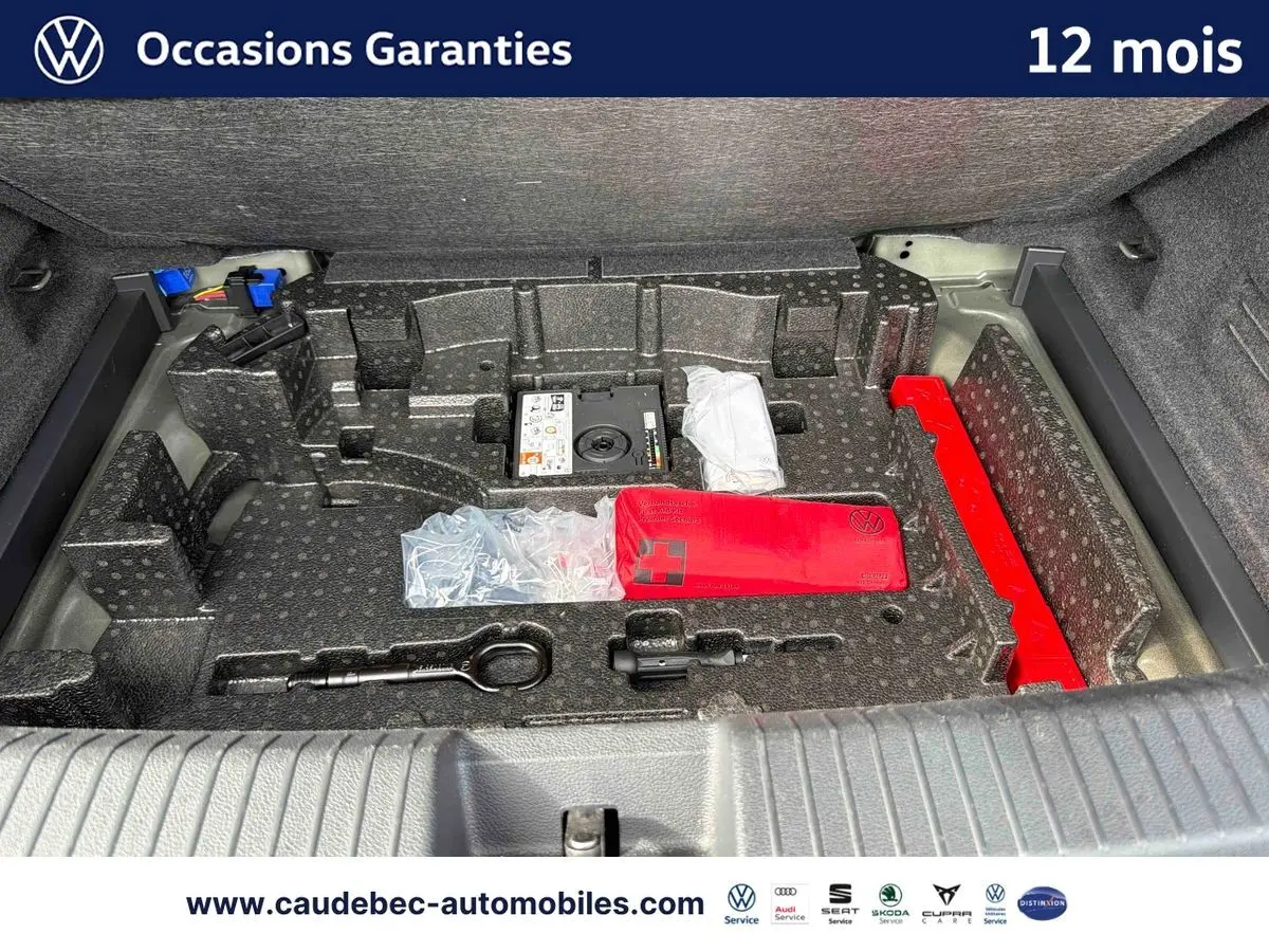 Coffre ouvert du Volkswagen T-Roc Cabriolet noir montrant le rangement avec kit de secours et outils intégrés.