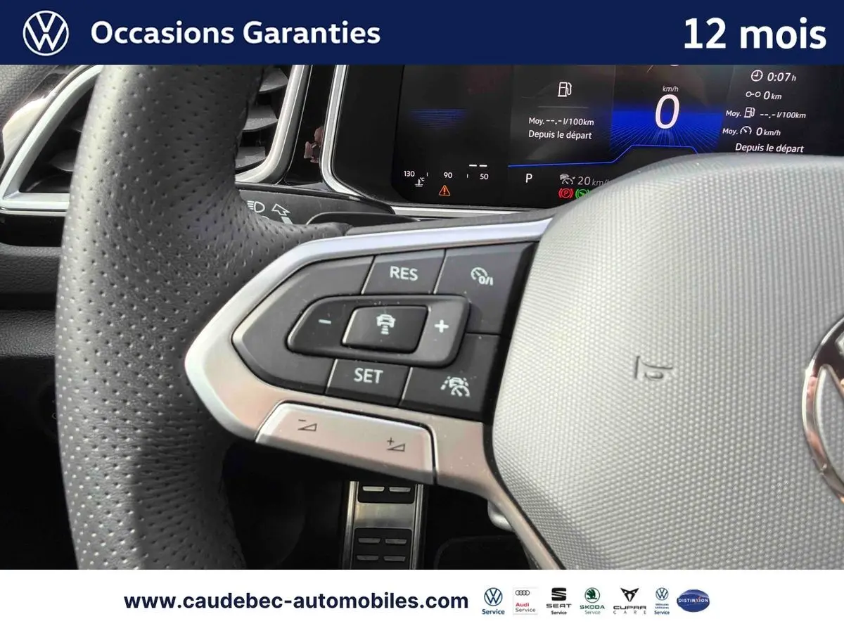 Gros plan sur le volant cuir perforé du Volkswagen T-Roc Cabriolet noir avec commandes multifonctions et tableau de bord digital.