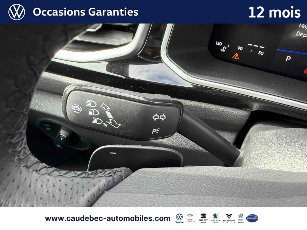 Gros plan sur le commodo gauche du volant en cuir perforé du Volkswagen T-Roc Cabriolet noir, avec tableau de bord numérique visible.