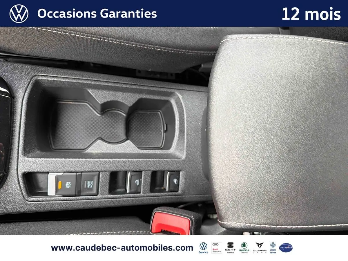 Vue plongeante sur la console centrale noire du Volkswagen T-Roc Cabriolet 2025 avec accoudoir et commandes électriques.