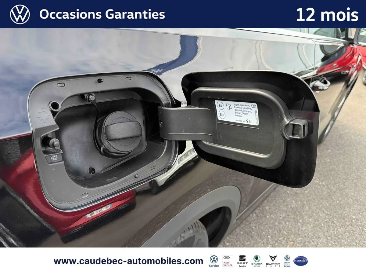 Vue rapprochée du bouchon de réservoir essence ouvert côté gauche sur Volkswagen T-Roc Cabriolet noire 2025.
