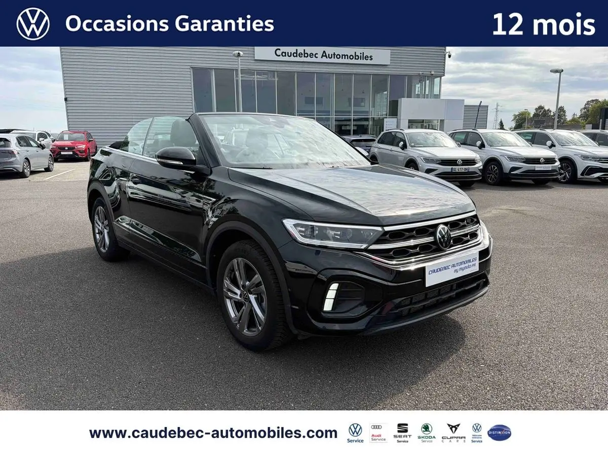 Volkswagen T-Roc Cabriolet noir vue 3/4 avant, toit ouvert, avec jantes alliage et calandre R-Line visible.