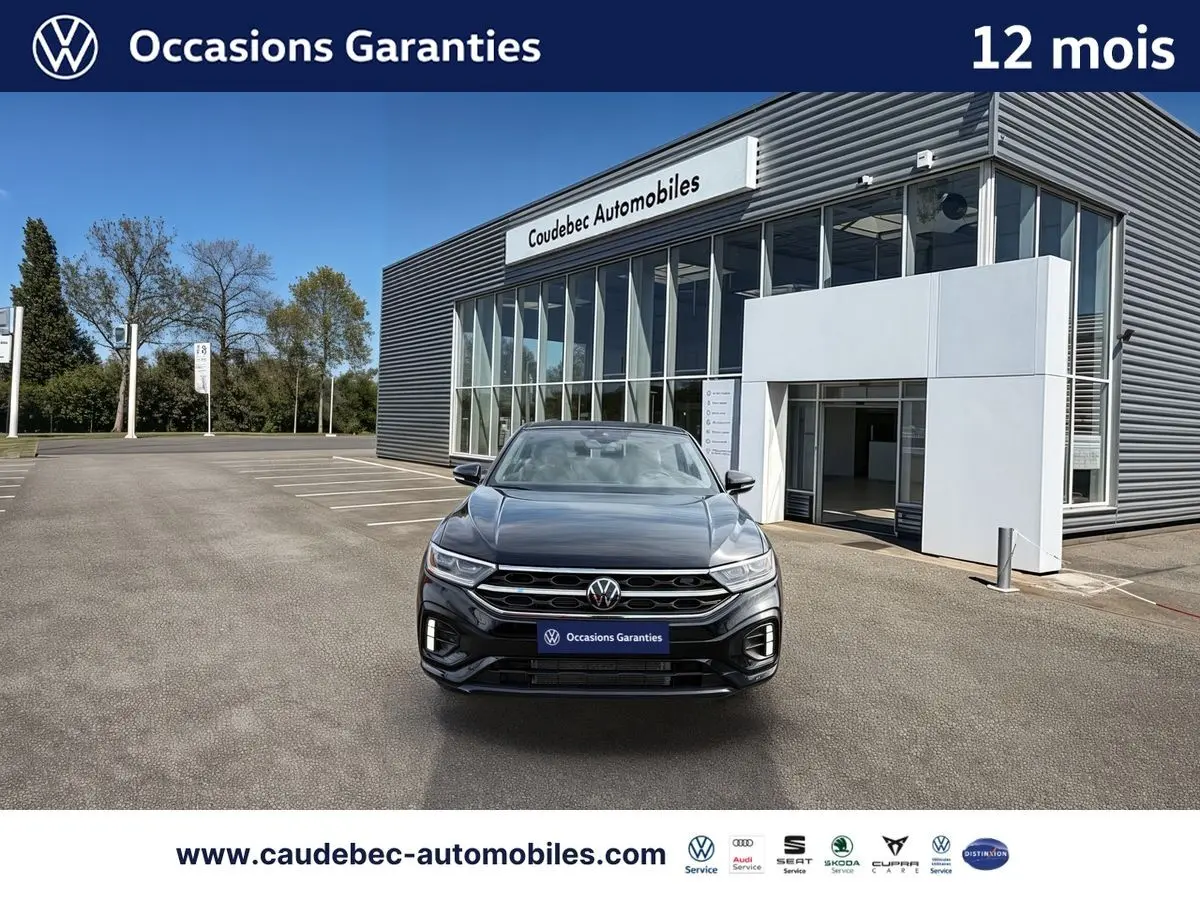 Volkswagen T-Roc Cabriolet noir vue de face, calandre R-Line et feux LED devant un showroom.