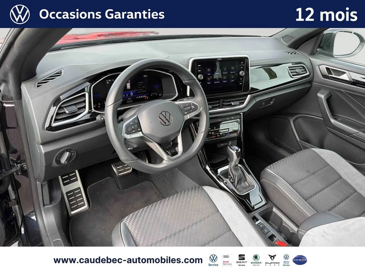 Vue intérieure côté conducteur du Volkswagen T-Roc Cabriolet noir, avec tableau de bord digital et volant multifonction.