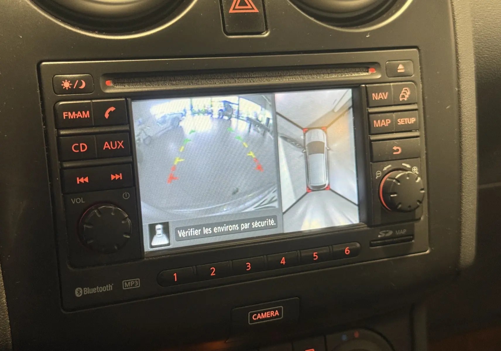 Écran de navigation et caméra de recul du Nissan Qashqai+2 gris 2014, vue rapprochée du tableau de bord.