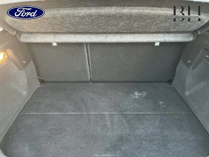 Coffre ouvert vu de l'intérieur, revêtement gris foncé, espace de rangement propre sans objet visible.