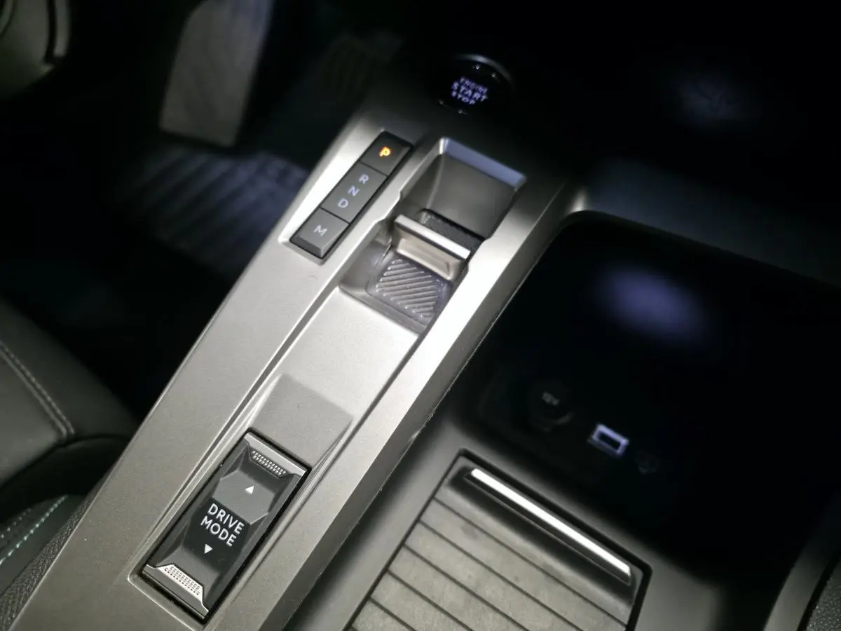 Gros plan sur la console centrale grise avec sélecteur de boîte auto et bouton Drive Mode de la Peugeot 308 SW noire.
