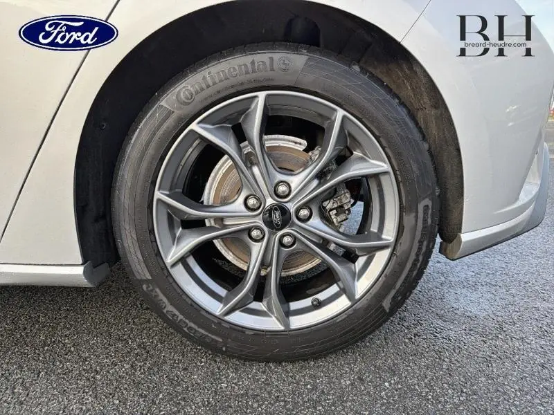 Gros plan sur la roue avant gauche d'une Ford Focus gris lunaire métallisé avec jante alu à design sportif.