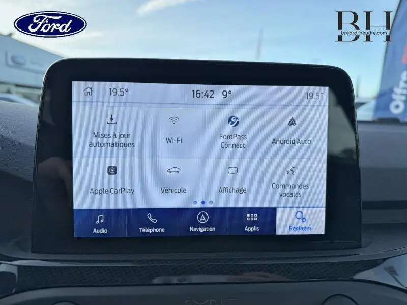 Écran tactile central affichant les options connectivité et réglages dans une Ford Focus gris lunaire 2019 vue de face intérieure.