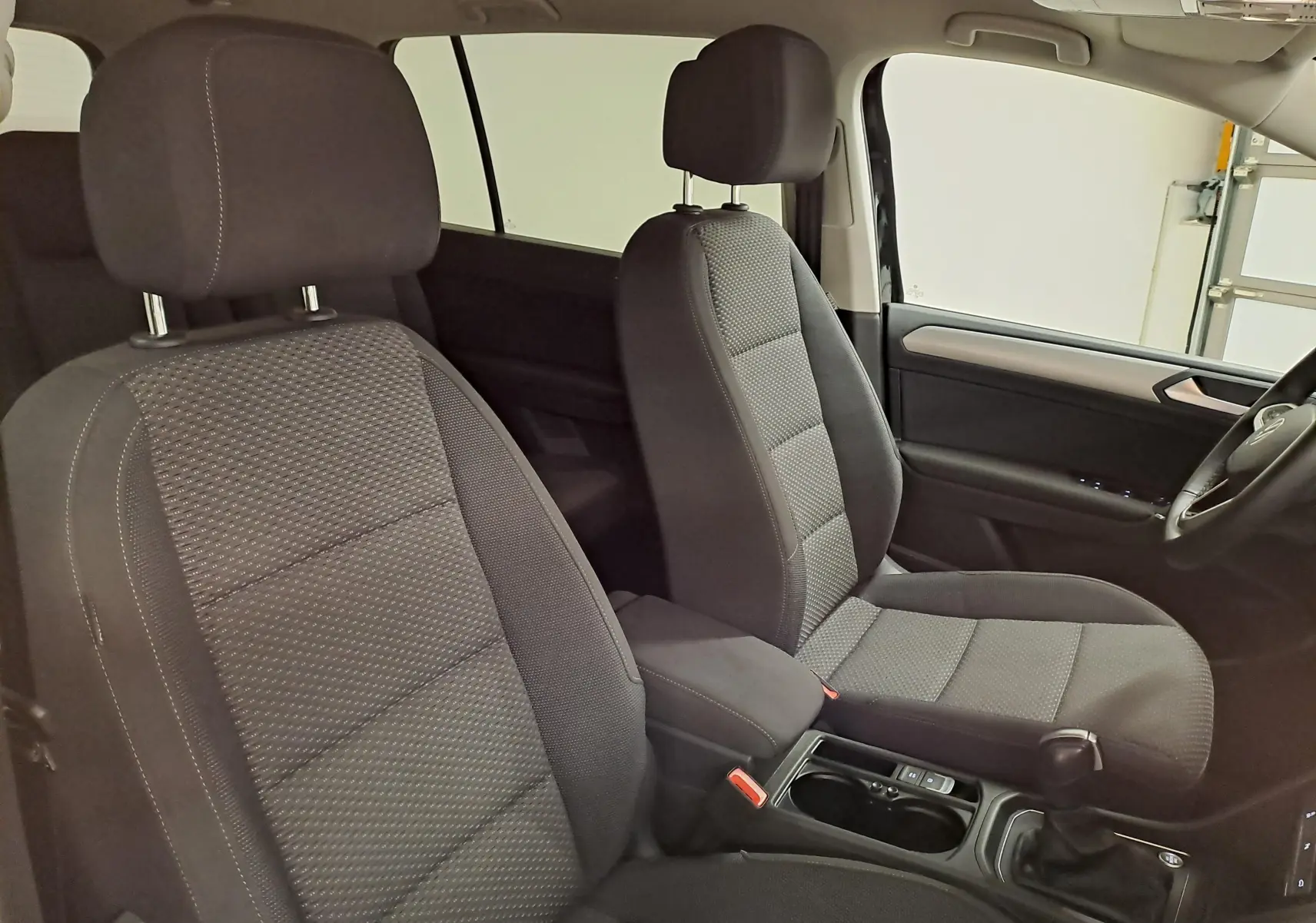 Vue intérieure côté droit montrant les sièges avant en tissu gris foncé du Volkswagen Touran 2025.