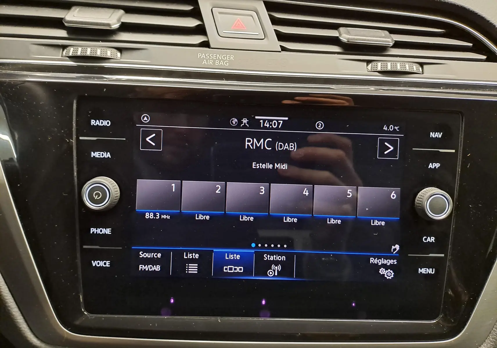 Écran tactile central du Volkswagen Touran 2025 affichant la radio DAB, avec commandes autour et finition noire brillante.