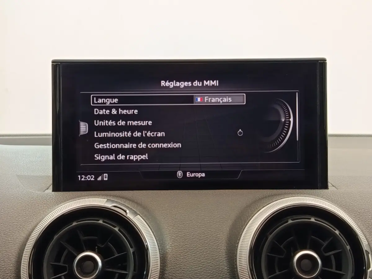 Écran central du système MMI affichant les réglages en français, avec deux aérateurs ronds en dessous, intérieur Audi Q2 2021.