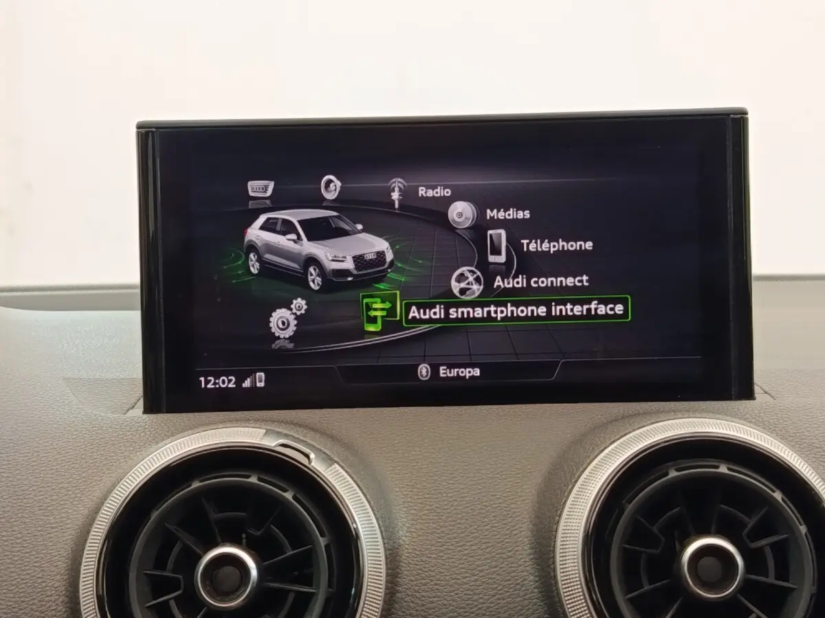 Écran central tactile montrant l'interface multimédia d'une Audi Q2 35 TFSI noire, tableau de bord en arrière-plan.