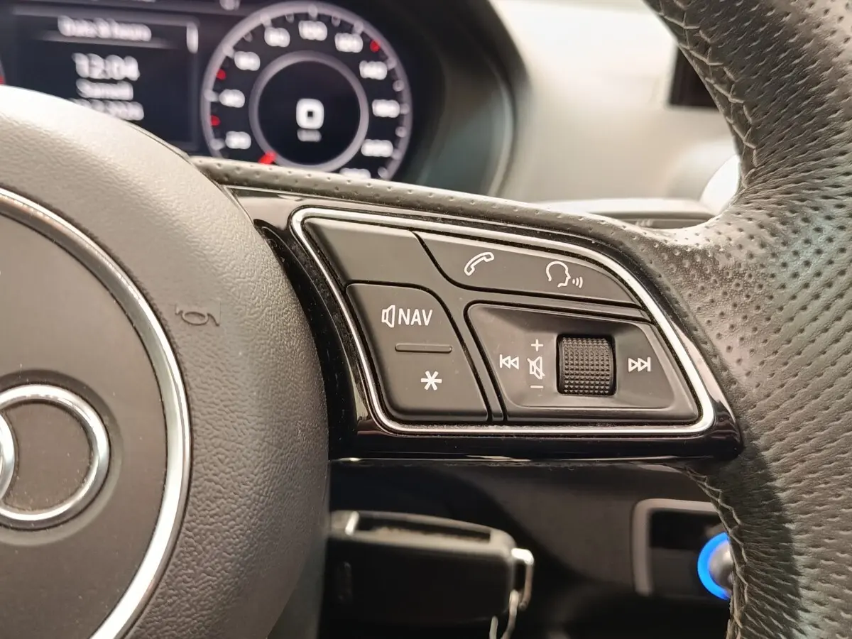 Gros plan sur le volant perforé noir de l’Audi Q2 35 TFSI avec commandes vocales et navigation intégrées.