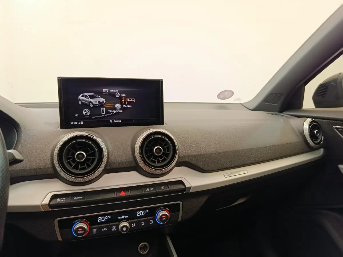 Intérieur de l'Audi Q2 35 TFSI 150 S Line 2021, vue du tableau de bord côté passager avec écran tactile et aérateurs ronds.