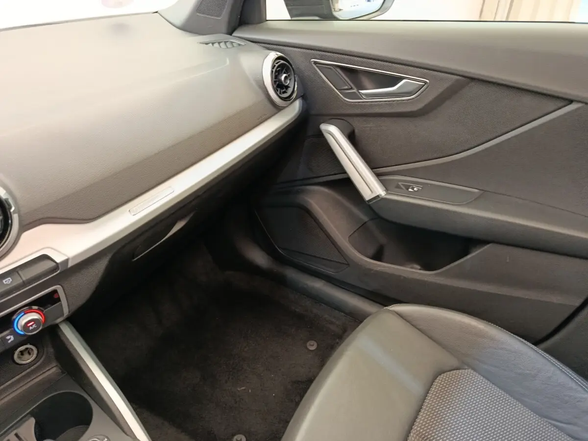 Intérieur côté passager de l’Audi Q2 35 TFSI noir, montrant la porte, siège et tableau de bord minimaliste.