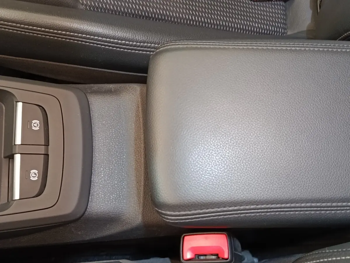 Gros plan sur la console centrale noire de l'Audi Q2 35 TFSI S Line 2021, avec accoudoir cuir et commandes frein électrique.