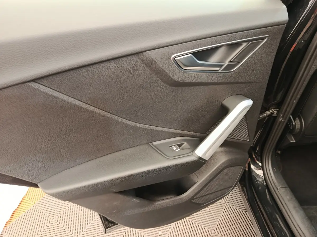 Gros plan sur la porte arrière droite noire de l'Audi Q2 35 TFSI 150 S Line avec poignée argentée et bouton de verrouillage.