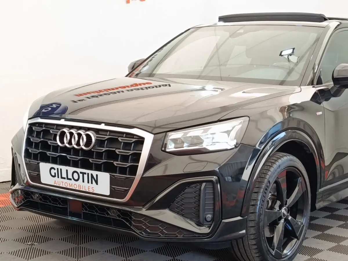 Audi Q2 35 TFSI S Line noir vue 3/4 avant droit, avec calandre hexagonale et jantes noires distinctives.