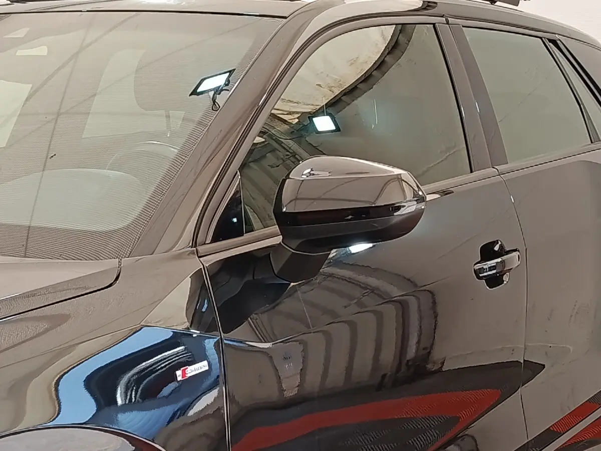 Vue latérale côté gauche d'un Audi Q2 noir 35 TFSI S Line avec logo S sur l'aile avant et rétroviseur noir brillant.
