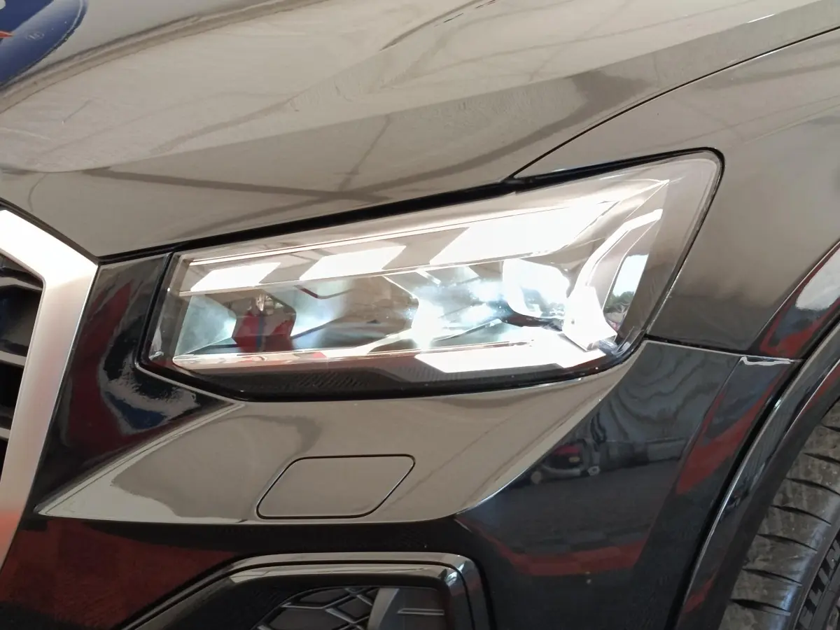Gros plan sur le phare avant droit noir brillant de l'Audi Q2 35 TFSI 150 S Tronic S Line 2021.