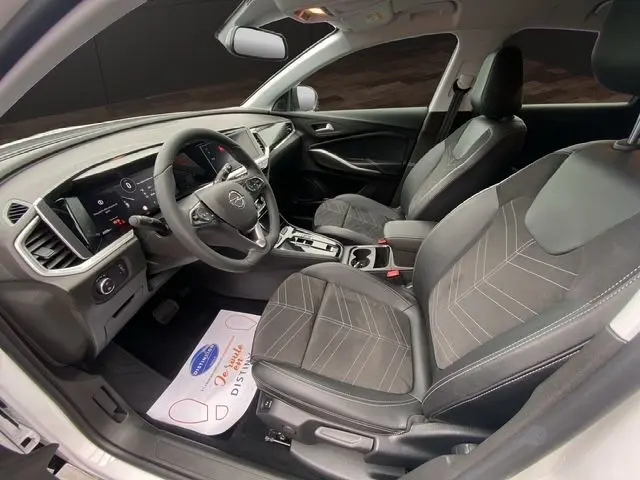 Intérieur avant droit de l’Opel Grandland blanc Arktis, sièges tissu/TEP gris avec surpiqûres claires et volant multifonction.