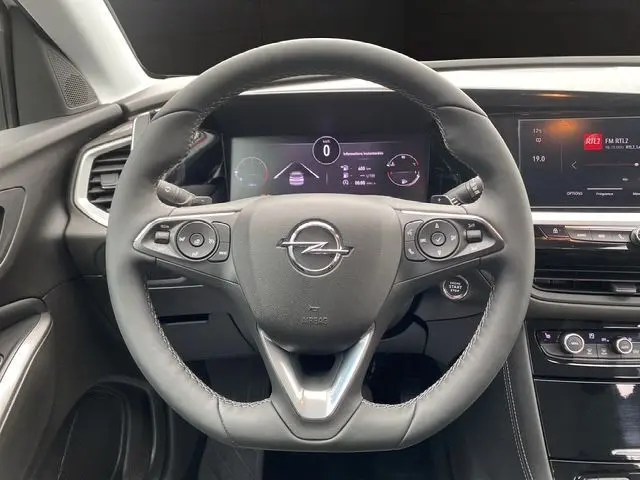 Volant cuir noir de l'Opel Grandland 2024 avec commandes intégrées et tableau de bord digital visible derrière.