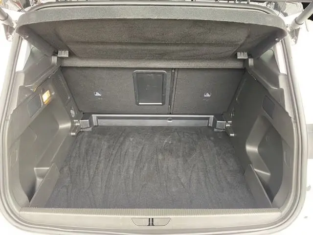 Coffre ouvert vu de l'arrière d'un Opel Grandland blanc Arktis au toit noir, montrant un espace de chargement propre et spacieux.