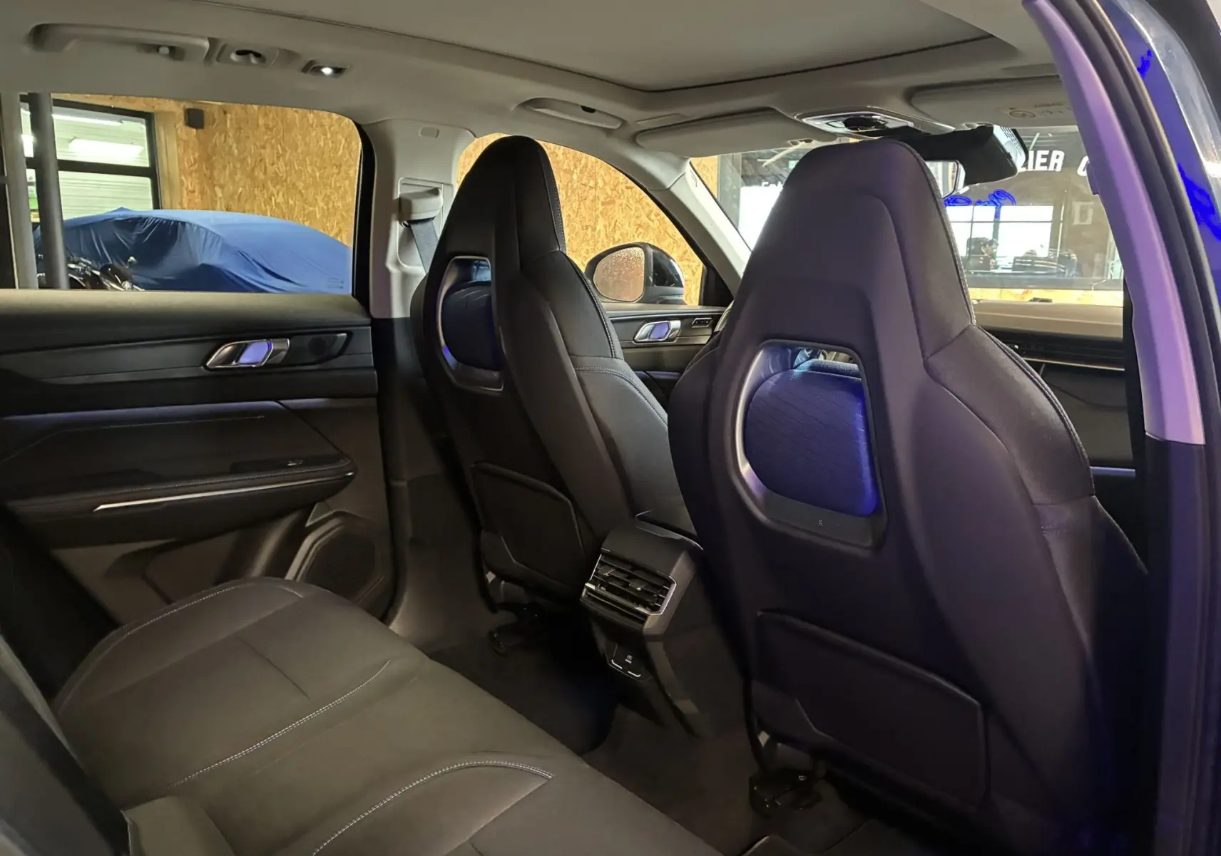 Intérieur arrière du LYNK & CO 01 bleu, vue côté gauche montrant sièges noirs avec détails bleus et aération centrale.