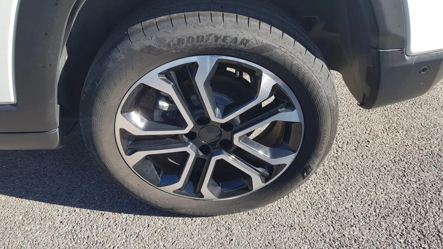 Gros plan sur la roue avant droite du Jeep Compass blanc 2024 avec jante alliage 18 pouces et pneu Goodyear.