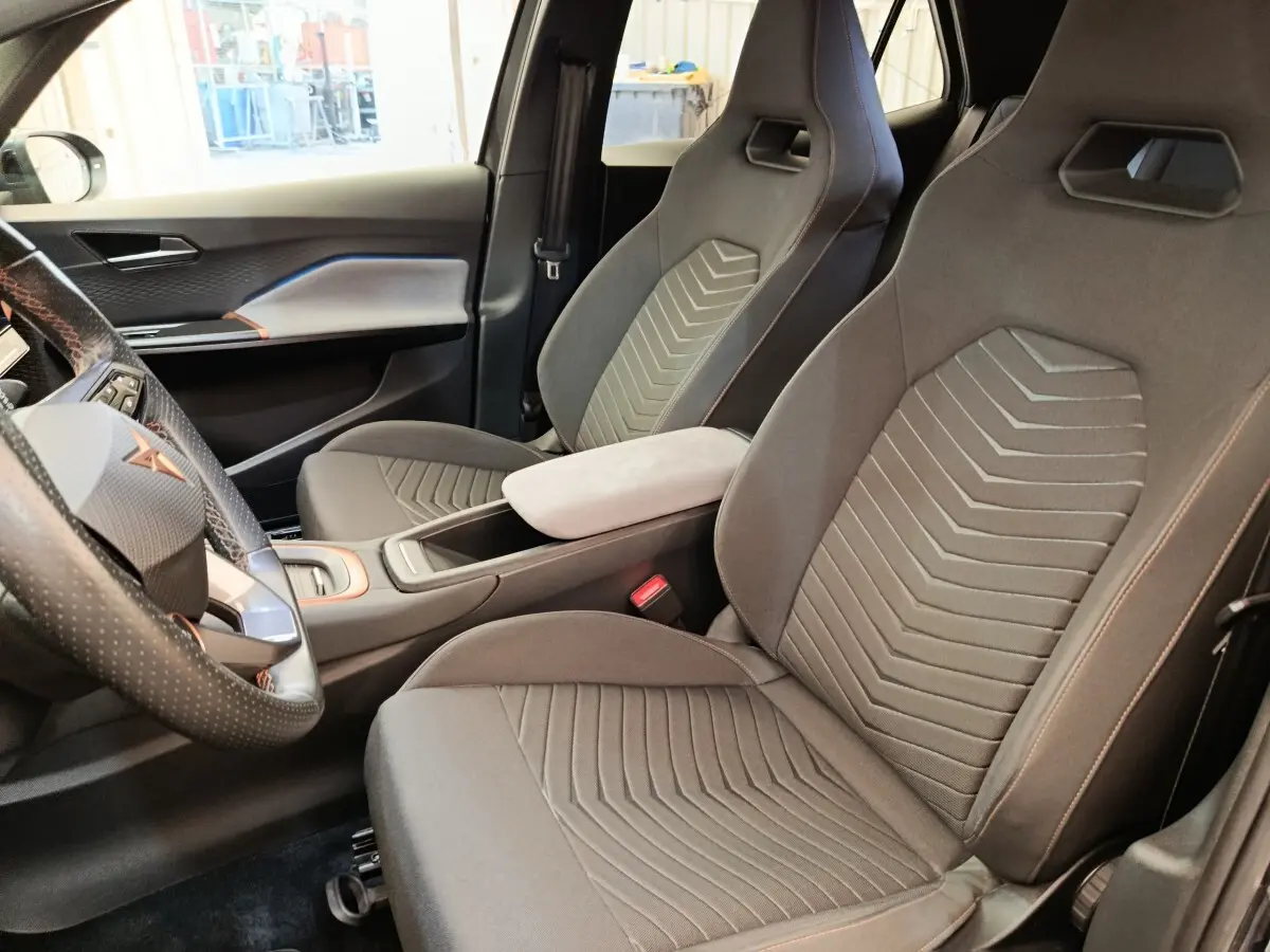 Vue intérieure côté conducteur du CUPRA Born 230ch gris foncé, avec sièges sport et volant cuir multifonctions.