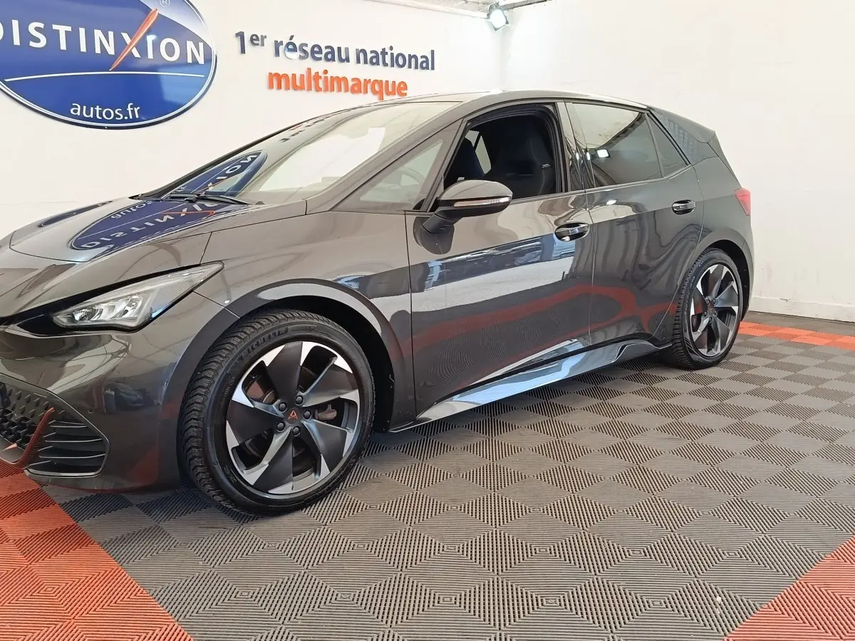 Vue 3/4 avant droit d'une CUPRA Born 230ch gris foncé électrique, avec jantes distinctives et intérieur visible.
