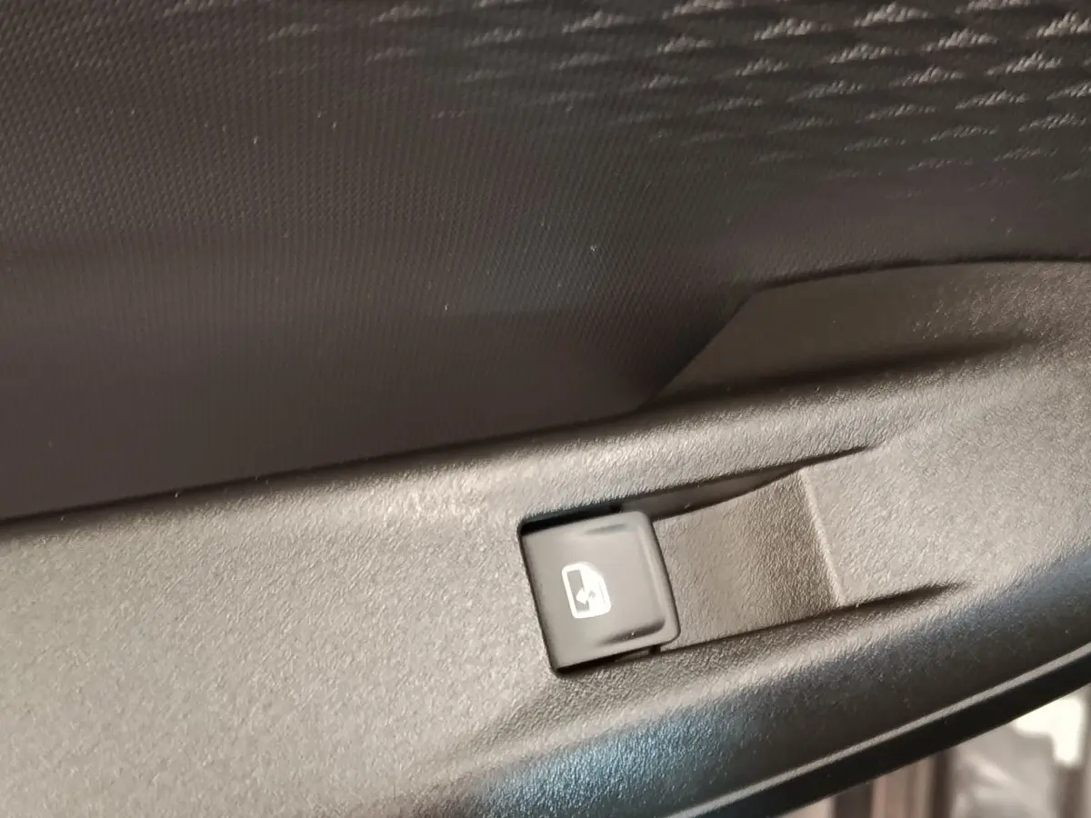 Bouton de commande de lève-vitre électrique sur la porte intérieure d'une CUPRA BORN gris foncé, vue rapprochée.